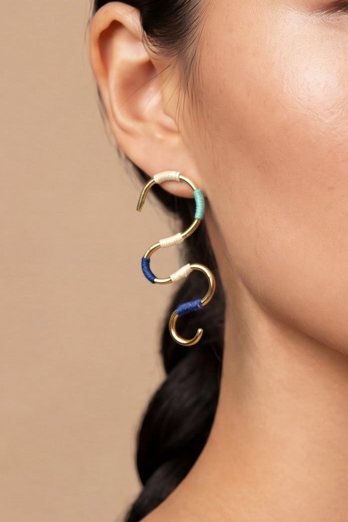 Woman wearing gold earrings against a beige background
